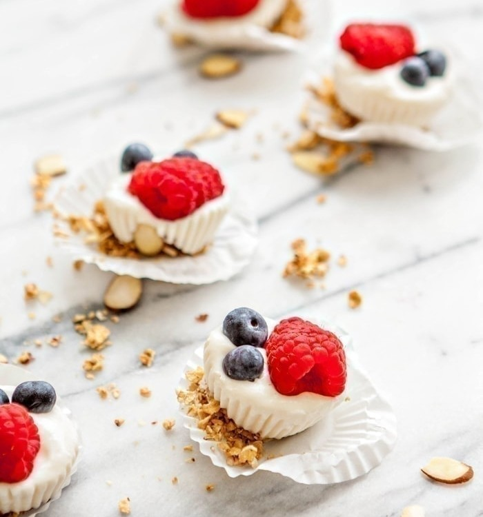 frozen yogurt bites topped with raspberries, blueberries, and granola
