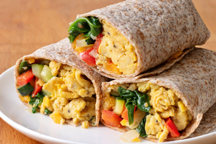 a whole wheat wrap with scrambled eggs, spinach, and bell peppers