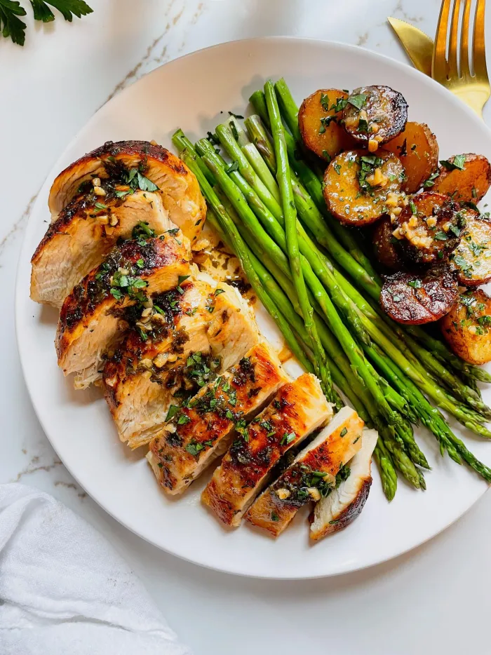 a plate with sliced grilled chicken, asparagus, and roasted potatoes 