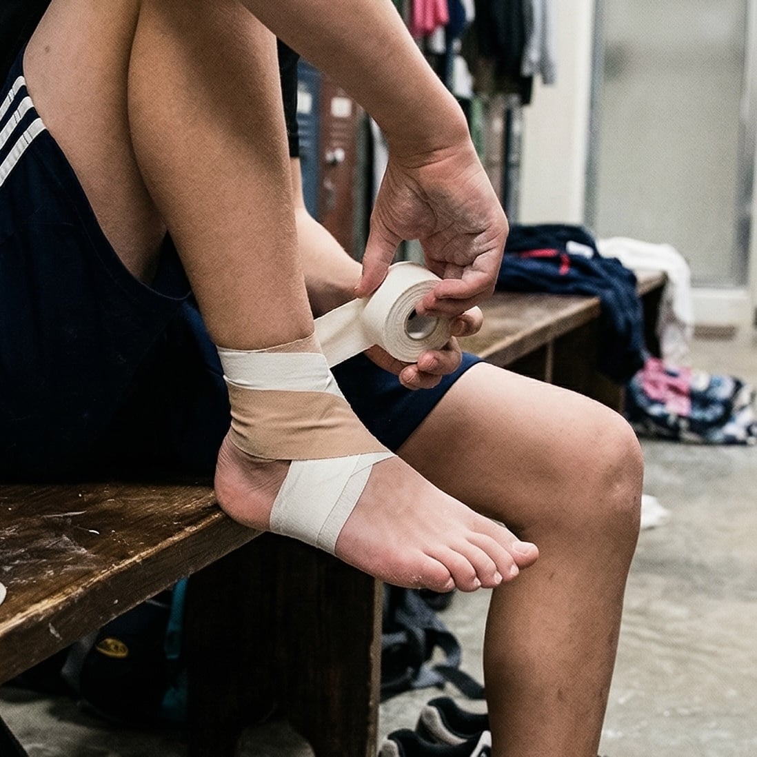 Gymnast taping their ankle after practice
