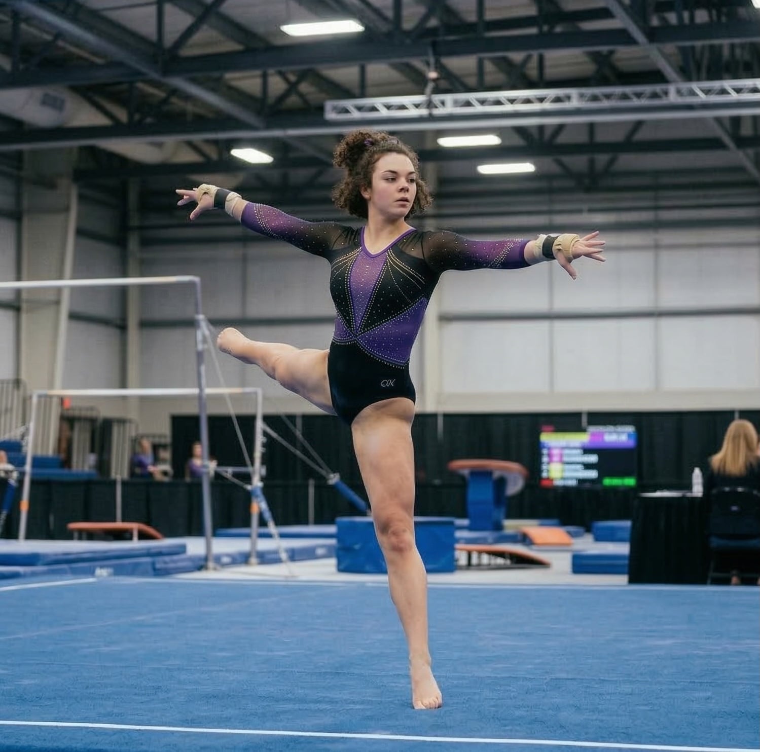 Competitive gymnast performing a leap in a purple competition leotard