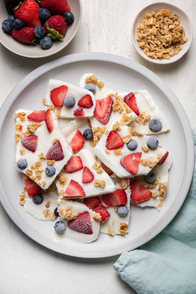 Image of a colorful frozen dessert bark with yogurt, berries, granola, and chocolate chips.