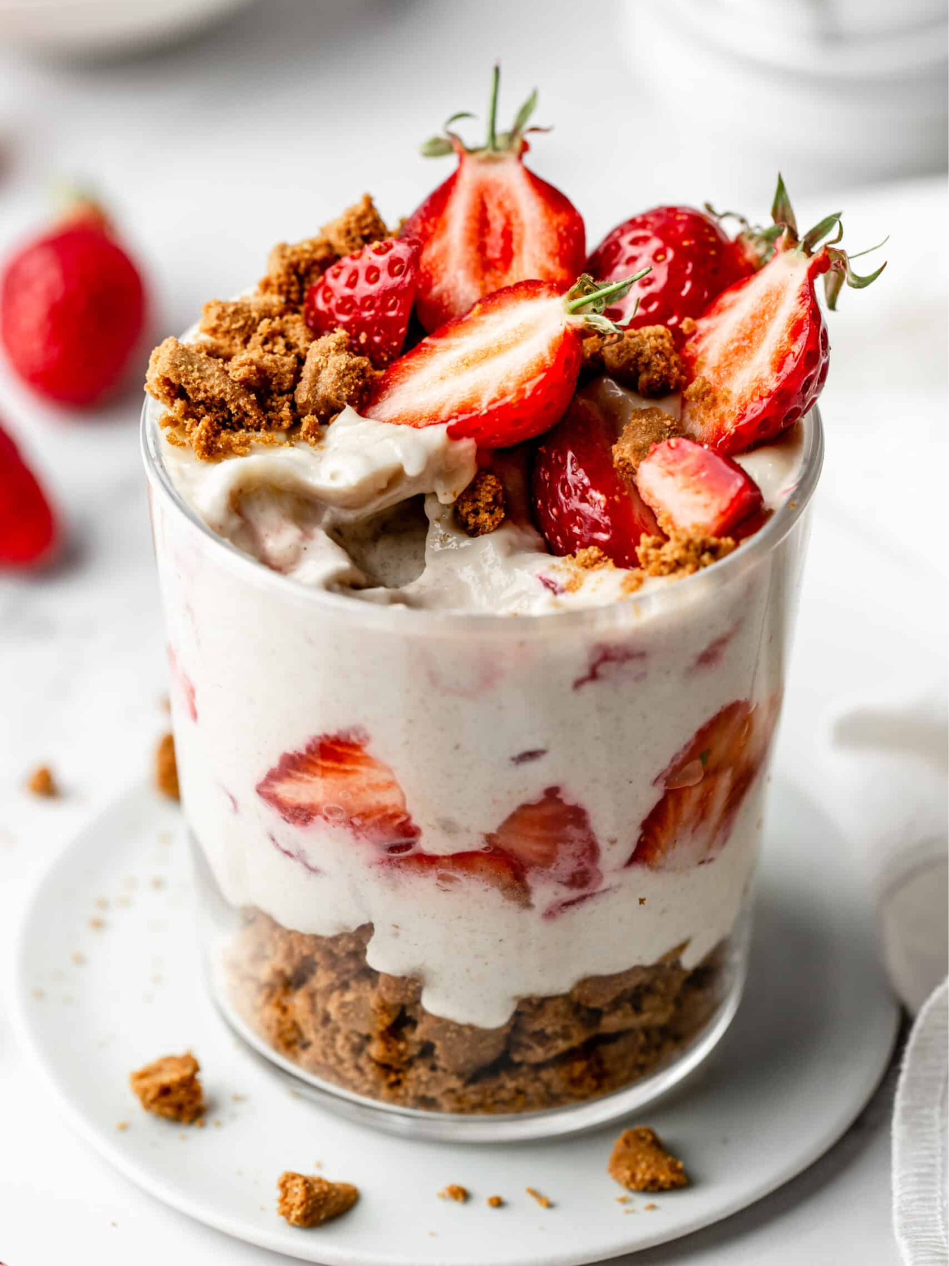 Write an alt text for the Strawberry Cheesecake Overnight Oats recipe image that describes a glass jar filled with layers of creamy overnight oats topped with fresh diced strawberries and a sprinkle of crushed graham crackers, highlighting its role as a nutritious and easy-to-grab post-gymnastics recovery snack.