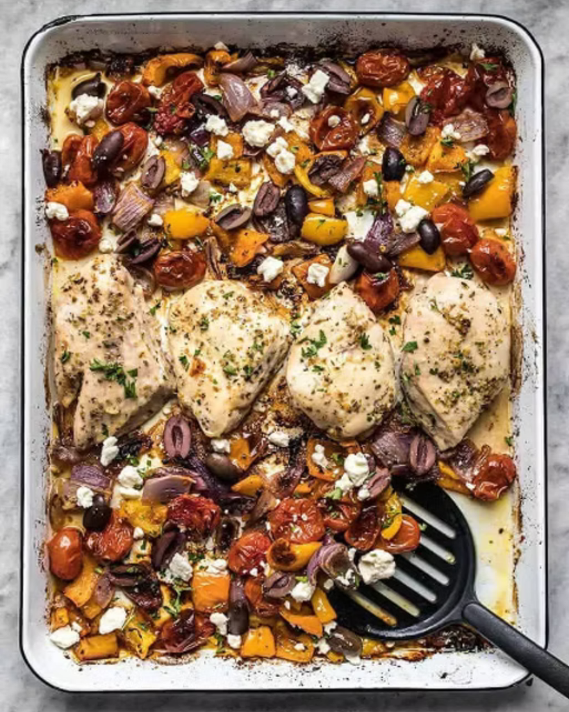 a roasting pan filled with seasoned chicken and greek vegetables 